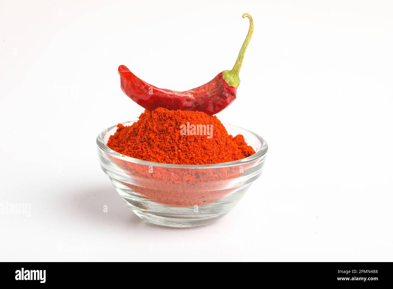 Piment rouge séché et poudre dans un bol en verre sur fond blanc. Banque D'Images