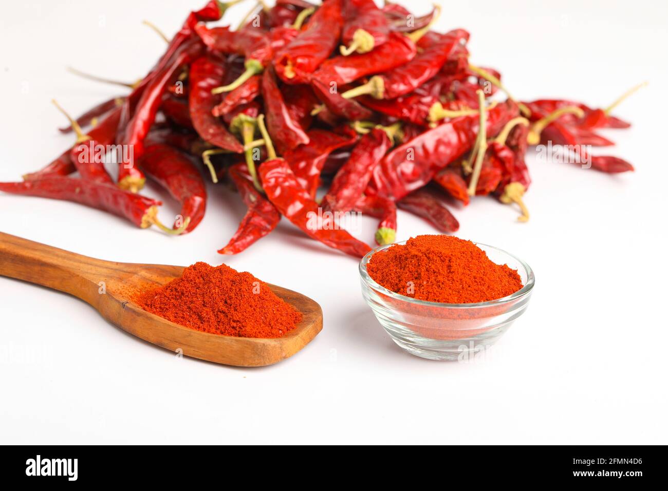 Piment rouge séché et poudre dans une cuillère en bois sur fond blanc. Banque D'Images