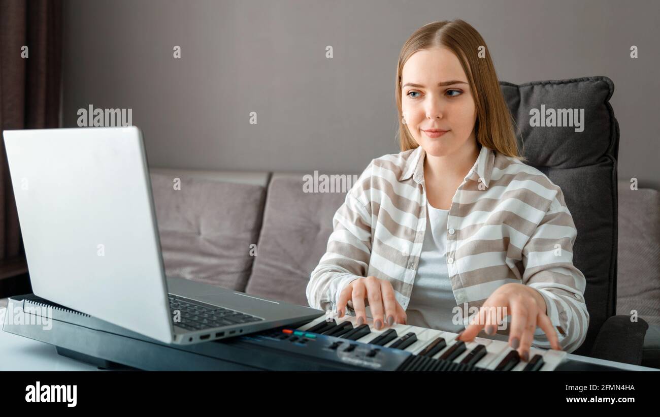 Femme apprend à jouer du piano en ligne en utilisant un ordinateur portable  à l'intérieur de la maison. Femme joue de l'instrument sur piano  synthétiseur pendant la leçon en ligne avec professeur.