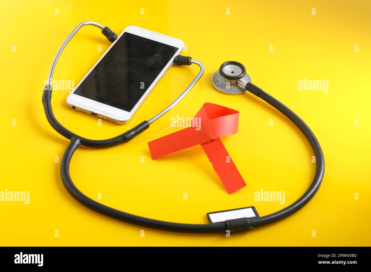 Smartphone et stéthoscope sur fond jaune. La technologie de la médecine en ligne (télémédecine). Service de diagnostic à distance, discutez avec un médecin. Banque D'Images