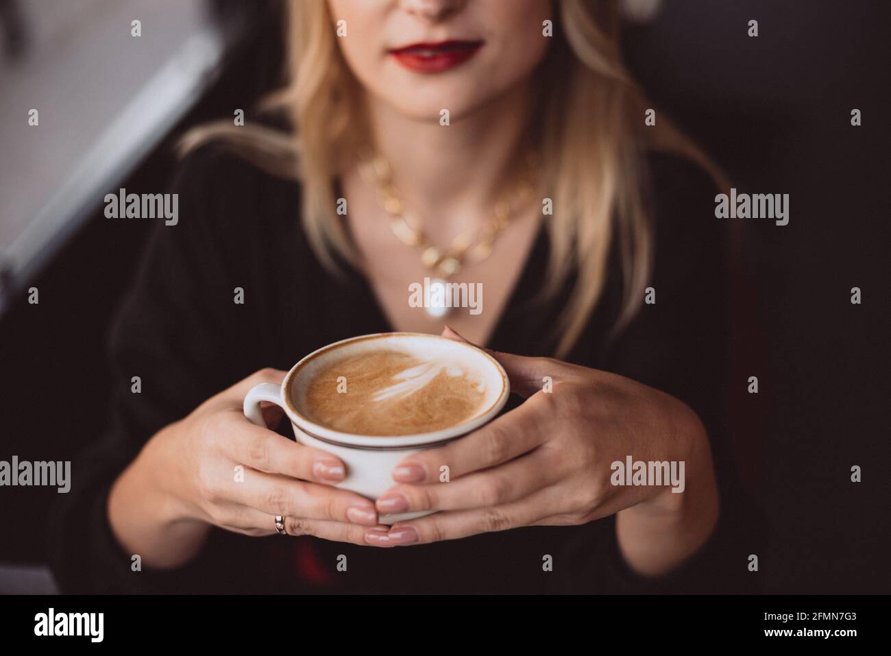 Belle jeune femme d'affaires aime une tasse de café dans un café pendant la pause déjeuner en automne. Mise au point sélective douce, bruit artistique. Banque D'Images