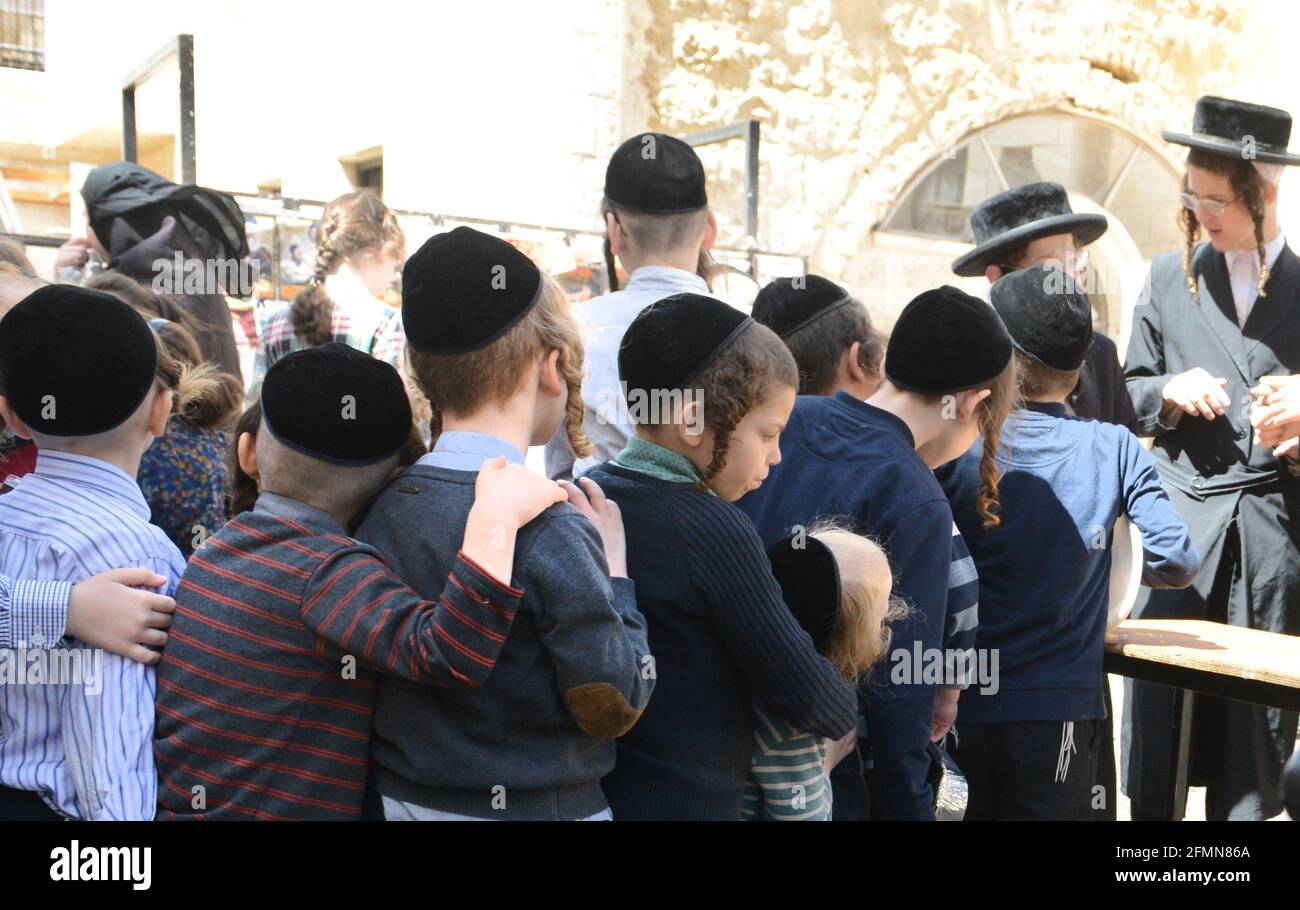 Des enfants orthodoxes juifs attendent en file pour de la nourriture et des bonbons servis par un homme juif juste pendant les préparatifs de la Pâque à MEA She'arim Jérusalem. Banque D'Images