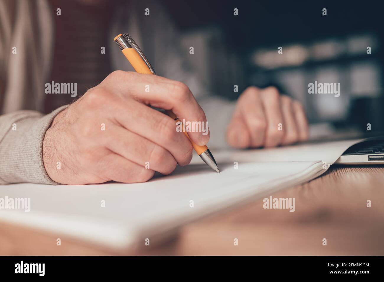 Travailleur indépendant qui écrit une liste de tâches au bureau à domicile, gros plan avec une attention sélective Banque D'Images