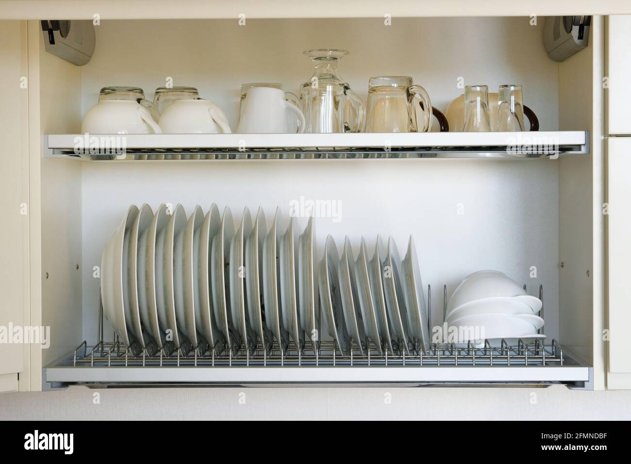 Étagère pour vaisselle séchage dans la cuisine moderne. Assiettes et tasses  en verre blanc et en céramique sur un support en métal à l'intérieur du  placard de la cuisine Photo Stock -