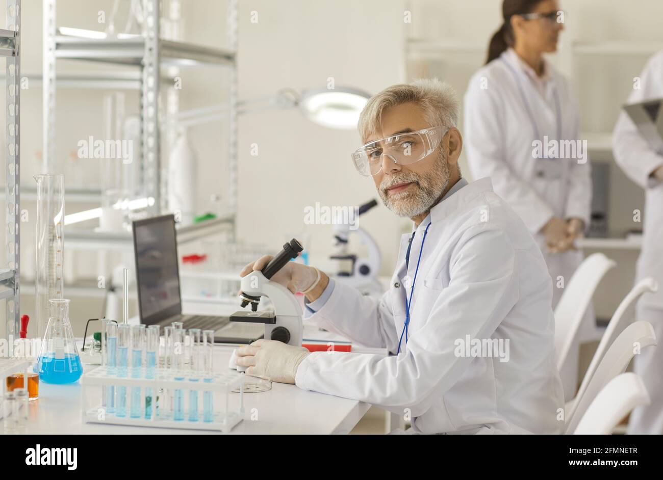 Portrait d'un scientifique expérimenté et expérimenté qui travaille au microscope dans un laboratoire. Banque D'Images