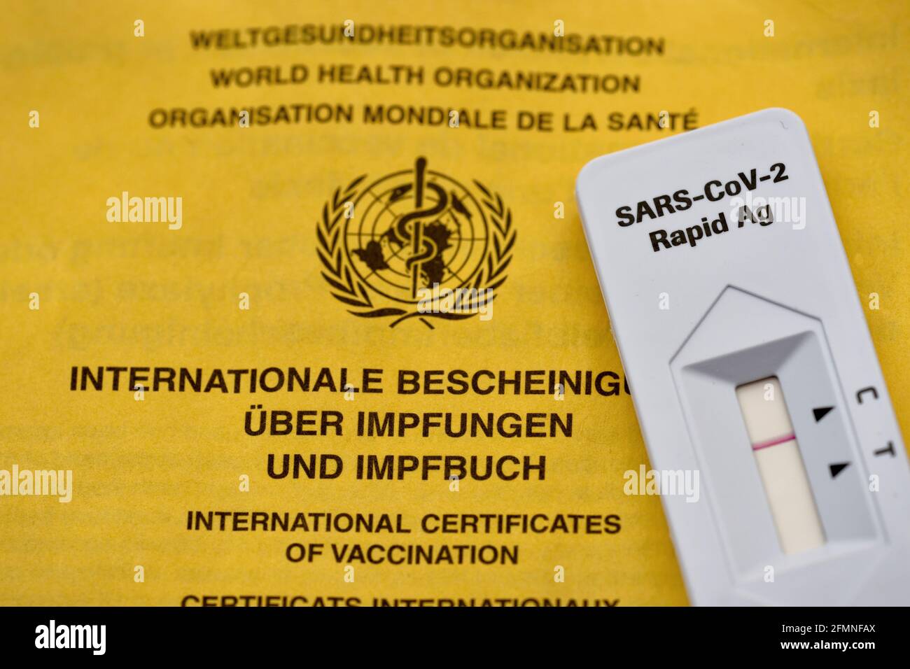 Test automatique d'antigène rapide Corona en face de l'UE jaune carte de vaccination en gros plan Banque D'Images Test automatique d'antigène rapide Corona en face de l'UE jaune carte de vaccination en gros plan Banque D'Images
