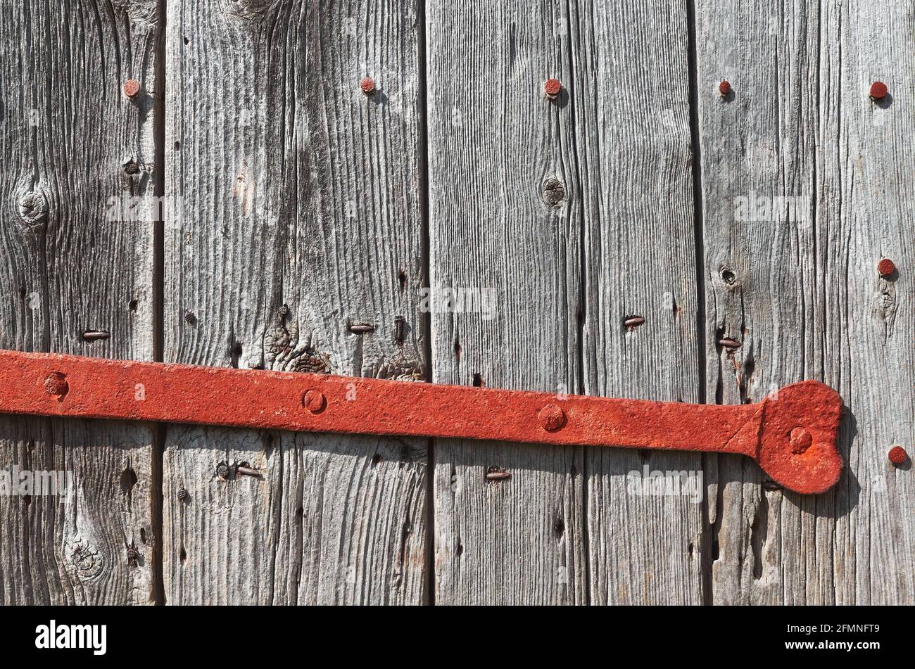 Gros plan d'une vieille porte en bois avec barre de verrouillage rouillée. Banque D'Images