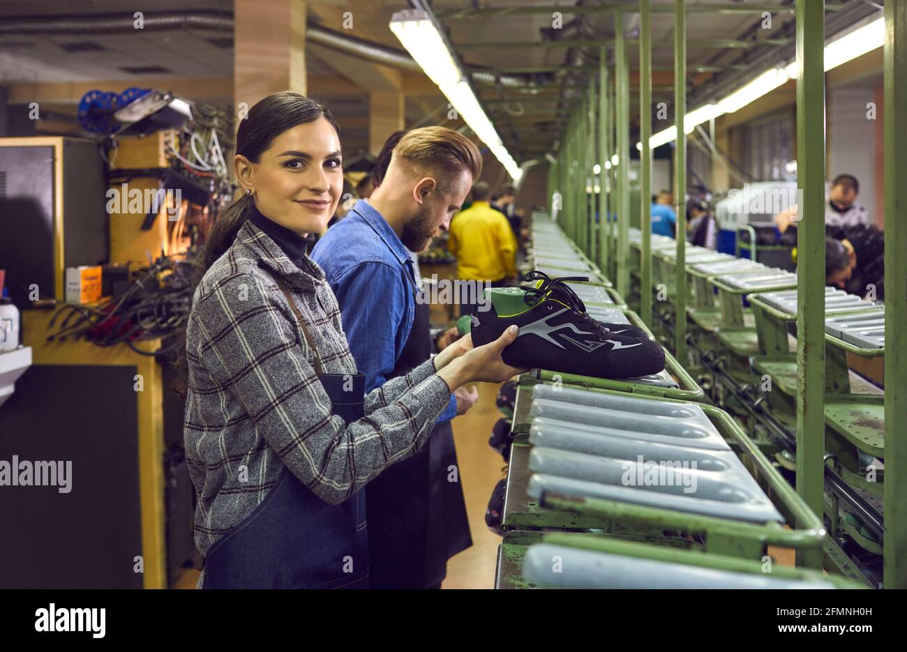 Équipe de cordonniers hommes et femmes travaillant sur la chaîne de production à usine de chaussures Banque D'Images