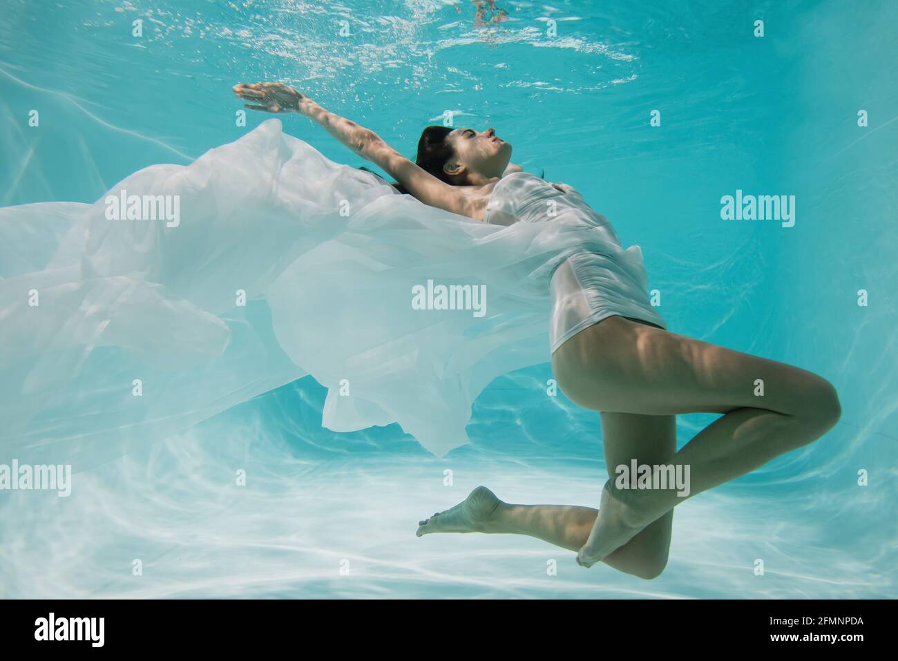 femme gracieuse en robe blanche plongée dans la piscine Banque D'Images