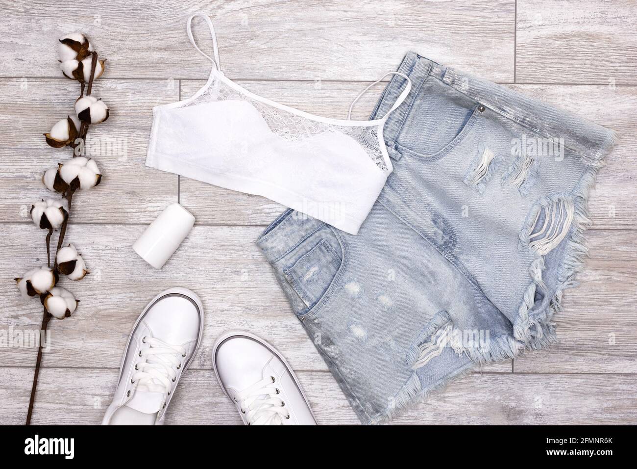 Tenue d'été pour femme. Short en denim bleu déchiré, soutien-gorge blanc,  baskets, déodorant à revers avec tige en coton. Articles essentiels pour  l'été Photo Stock - Alamy