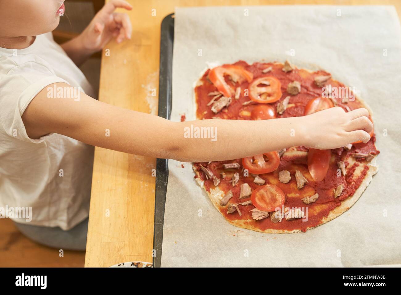 La jeune fille prépare une pizza sans gluten saine avec du bœuf. Cours de cuisine sans gluten. Cuisiner ensemble à la maison avec un parent. Recette étape par étape Banque D'Images