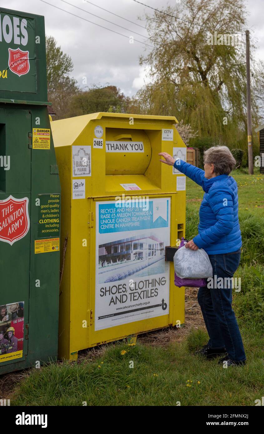 Hampshire, Angleterre, Royaume-Uni. 2021. Femme faisant don de vêtements pour une œuvre de charité en utilisant un conteneur de collecte communautaire pour la charité dans un village du Hampshire. Banque D'Images