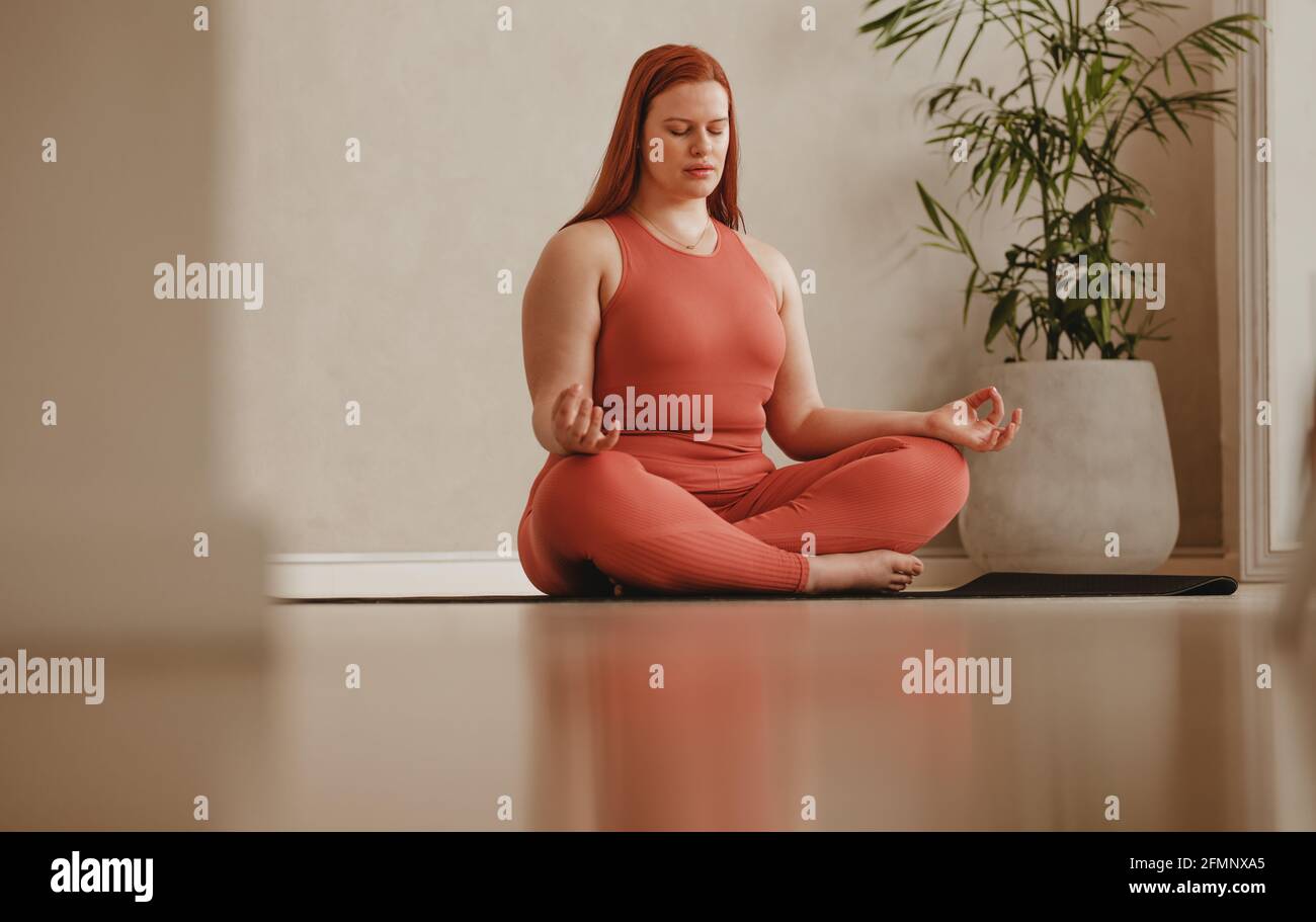 Femme de sport faisant de l'entraînement de yoga de relaxation à la maison. Femme assise sur une posture de méditation au studio de fitness. Banque D'Images