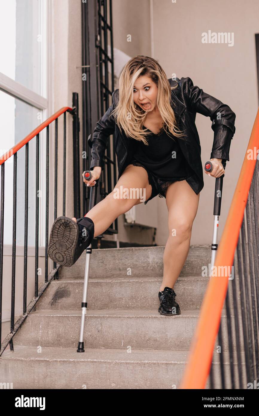 Une jeune femme sur des béquilles en orthèse tombe dans les escaliers. Pas  d'ascenseur pour les personnes à mobilité réduite. Photo d'humour. Concept  assurance accident Photo Stock - Alamy
