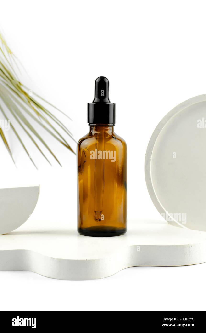 Sérum dans un flacon en verre avec une pipette. Huile essentielle naturelle sur un podium blanc. Emballage d'un produit cosmétique. Banque D'Images