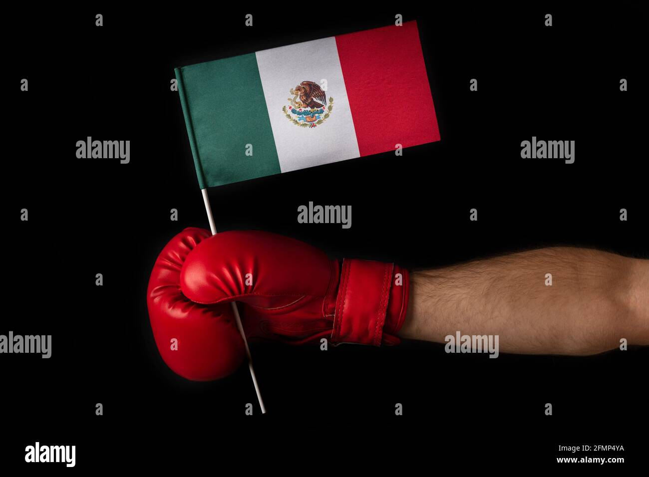 La main de boxer tient le drapeau du Mexique. Gant de boxe avec drapeau mexicain. Arrière-plan noir Banque D'Images