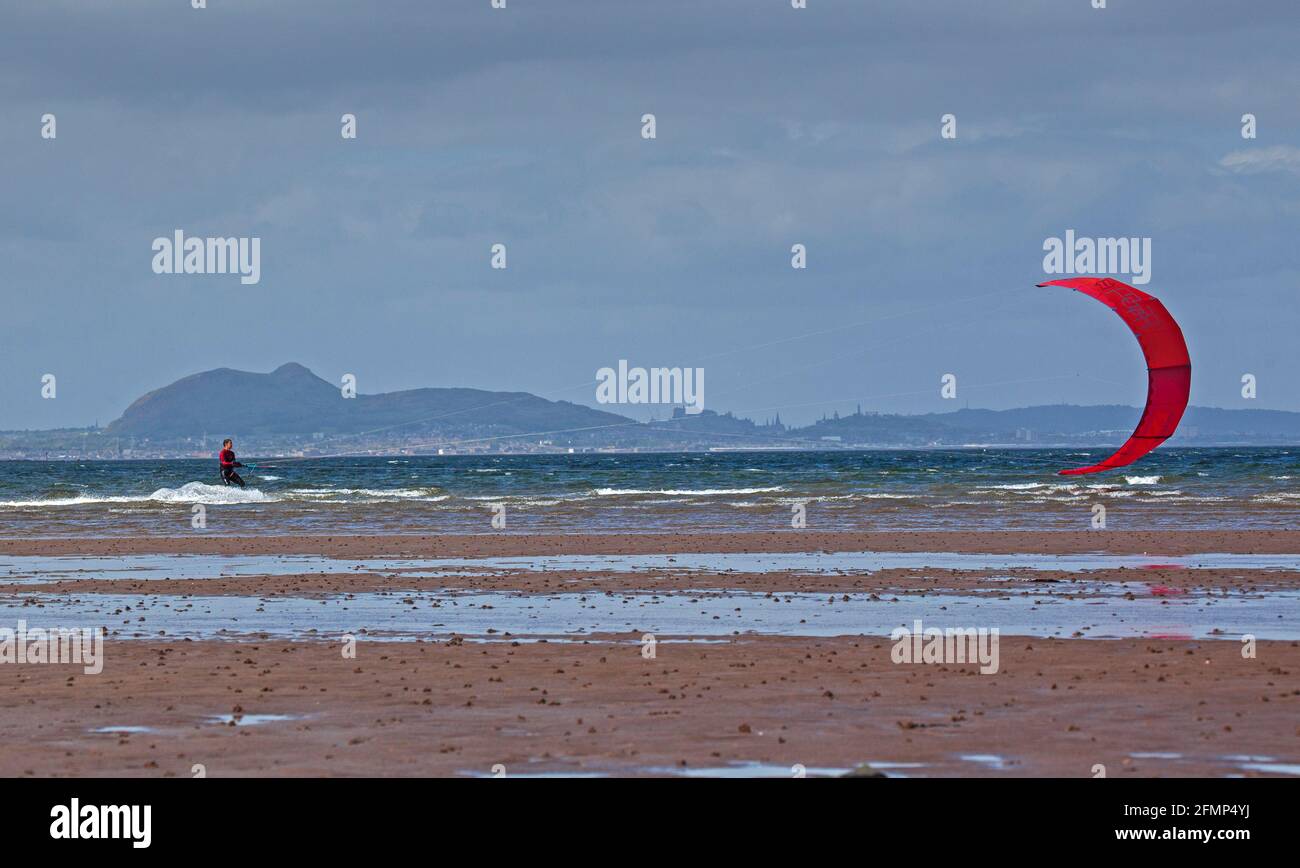 Longniddry, East Lothian, Écosse, météo britannique. 11 mai 2021. Vent et soleil pour un Kitesurfer sur le Firth of Forth. Marée très basse à Longniddry Bents avec la ville d'Édimbourg en arrière-plan. Le fait que ce type ait imprimé Rebel sur son cerf-volant pourrait expliquer pourquoi il est le seul à brasser les éléments. Vents de 21 km/h avec des rafales potentielles de 36 km/h. Crédit : Arch White/Alamy Live News. Banque D'Images