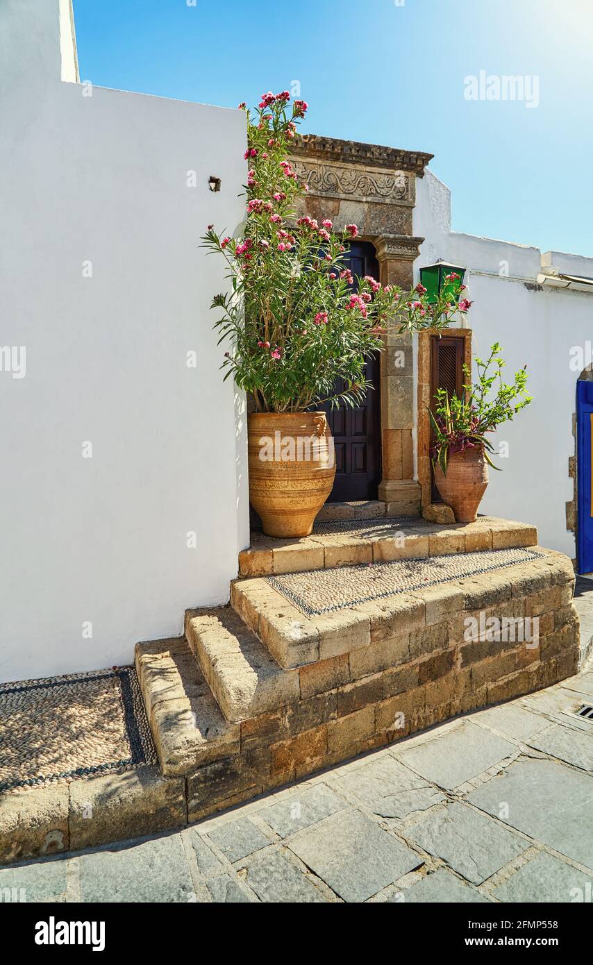 Rues étroites et escarpées avec murs blanchis à la chaux et arbustes en fleurs Et les vieux escaliers dans la ville grecque historique Lindos sous bleu ciel Banque D'Images