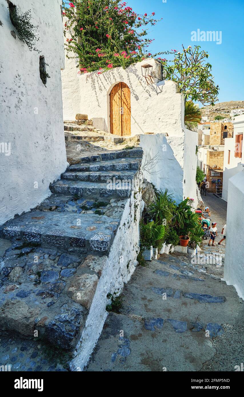 Rues étroites et escarpées avec murs blanchis à la chaux et arbustes en fleurs Et les vieux escaliers dans la ville grecque historique Lindos sous bleu ciel Banque D'Images