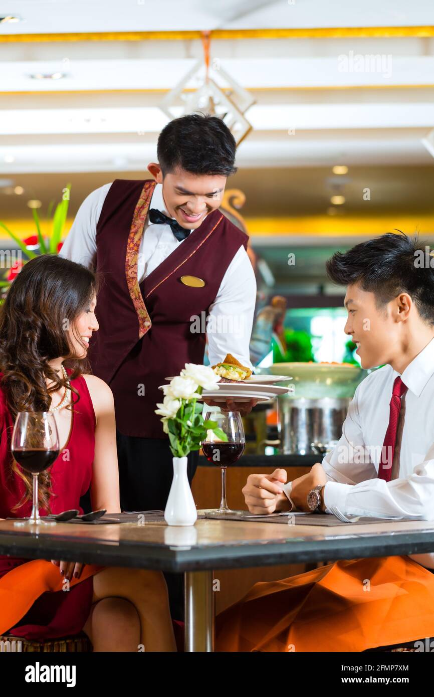 Chinois asiatique couple - Homme et femme - ou en amoureux dont la date ou  un dîner romantique dans un restaurant chic alors que le serveur est de  servir des aliments Photo