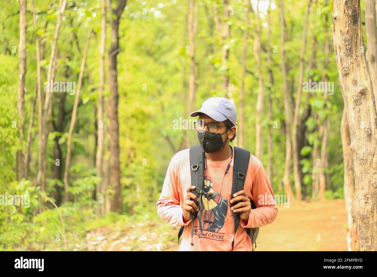 Un jeune Indien de 18-25 ans portant une casquette et un masque au milieu d'une pandémie de Covid-19 et marchant librement et indépendamment dans une jungle. Banque D'Images