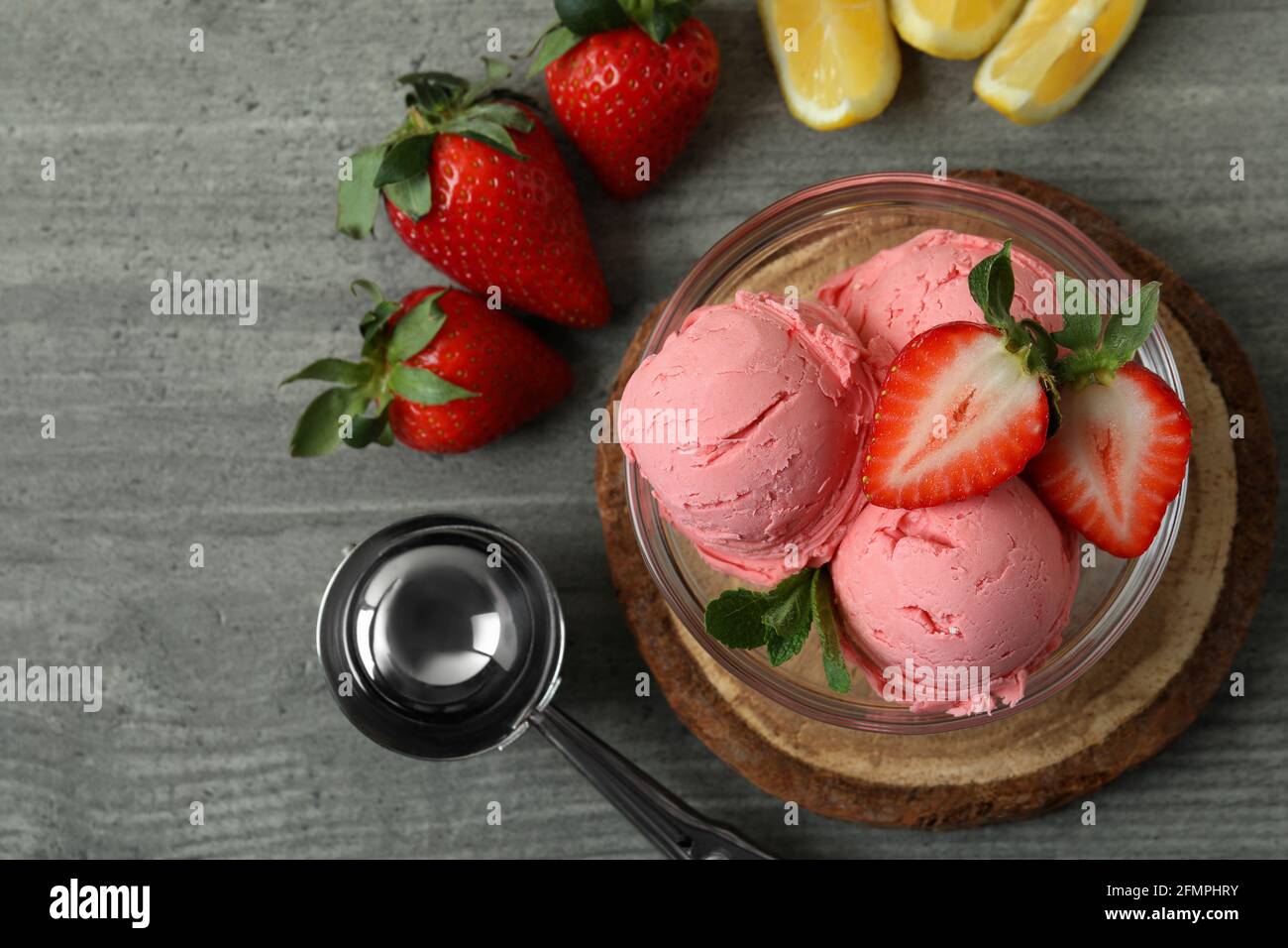 Bol avec boules de crème glacée et ingrédients sur texture grise arrière-plan Banque D'Images