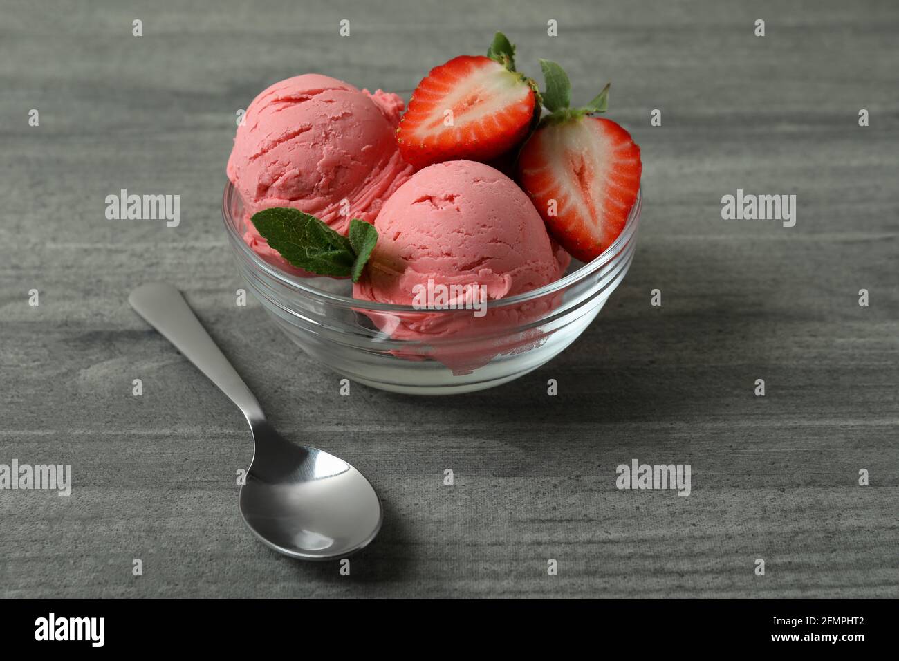 Bol avec boules de glace à la fraise sur table texturée grise Banque D'Images
