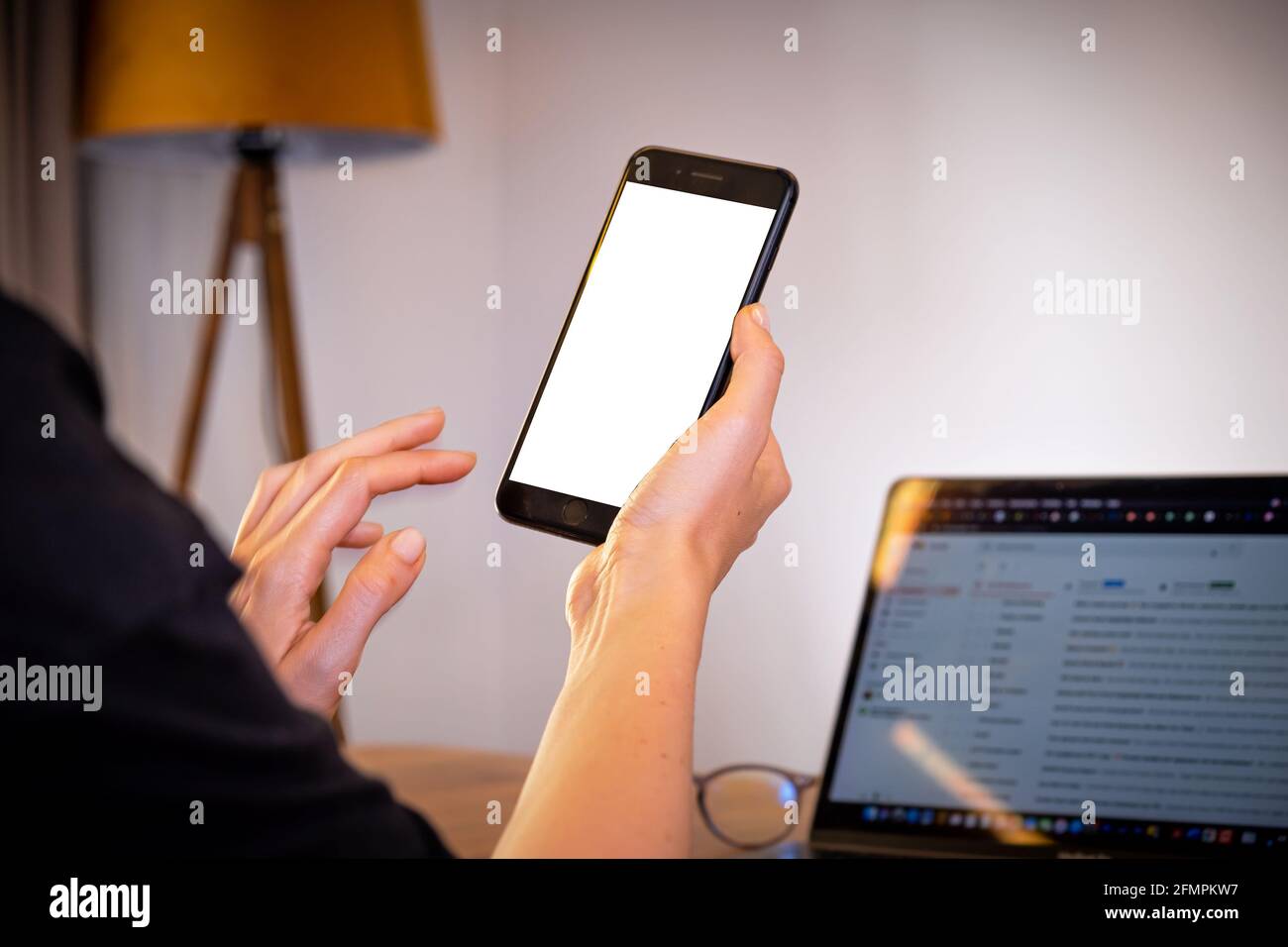 femme mains tenant le smartphone à la maison avec ordinateur portable sur table, achats en ligne Banque D'Images