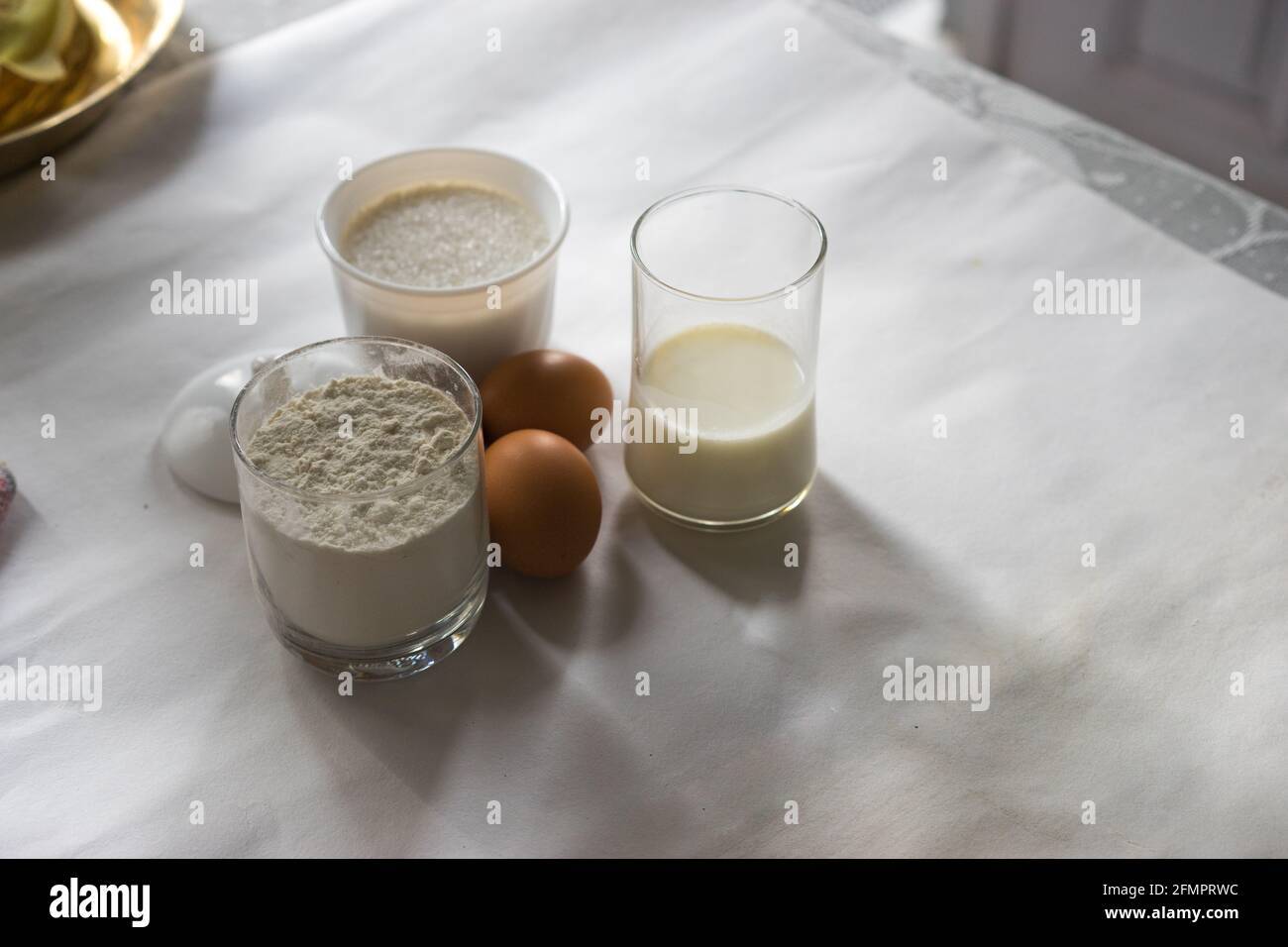 Ingrédients pour faire des crêpes pour le petit déjeuner à la maison sur la table: Oeufs frais, farine blanche, sucre, verre de lait. Cuisson pendant le verrouillage, kitc domestique Banque D'Images