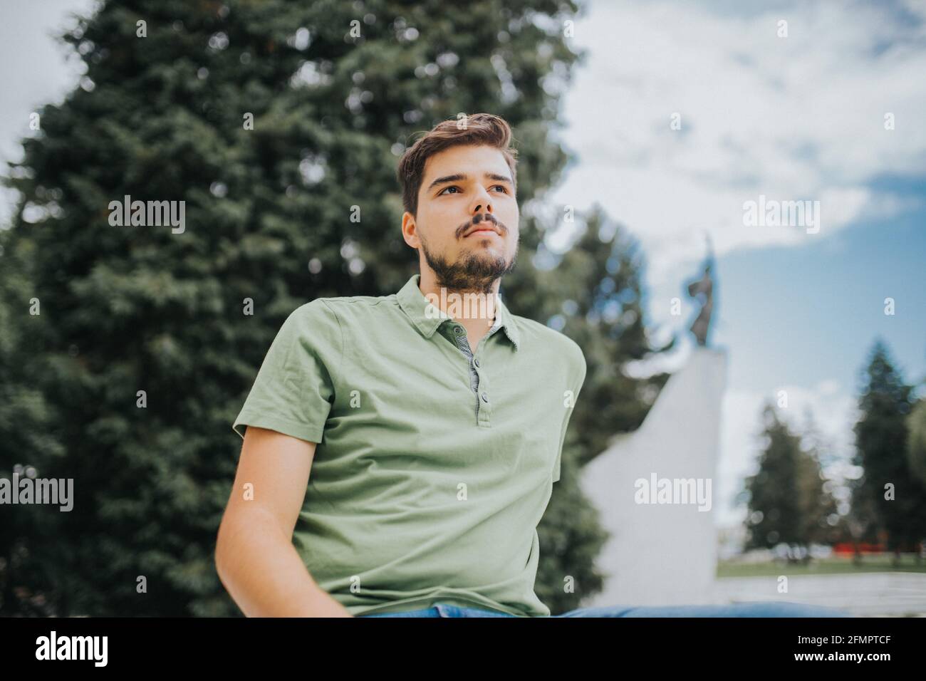 Prise de vue à angle bas d'un jeune homme caucasien attrayant avec une expression sérieuse posant à l'extérieur Banque D'Images