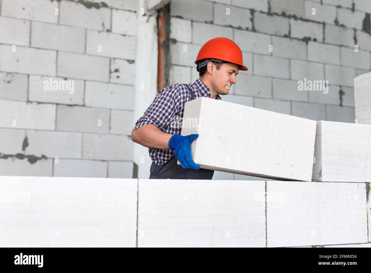 bricklayer man builder travaillant avec des blocs de béton cellulaire autoclavés. Mural Banque D'Images