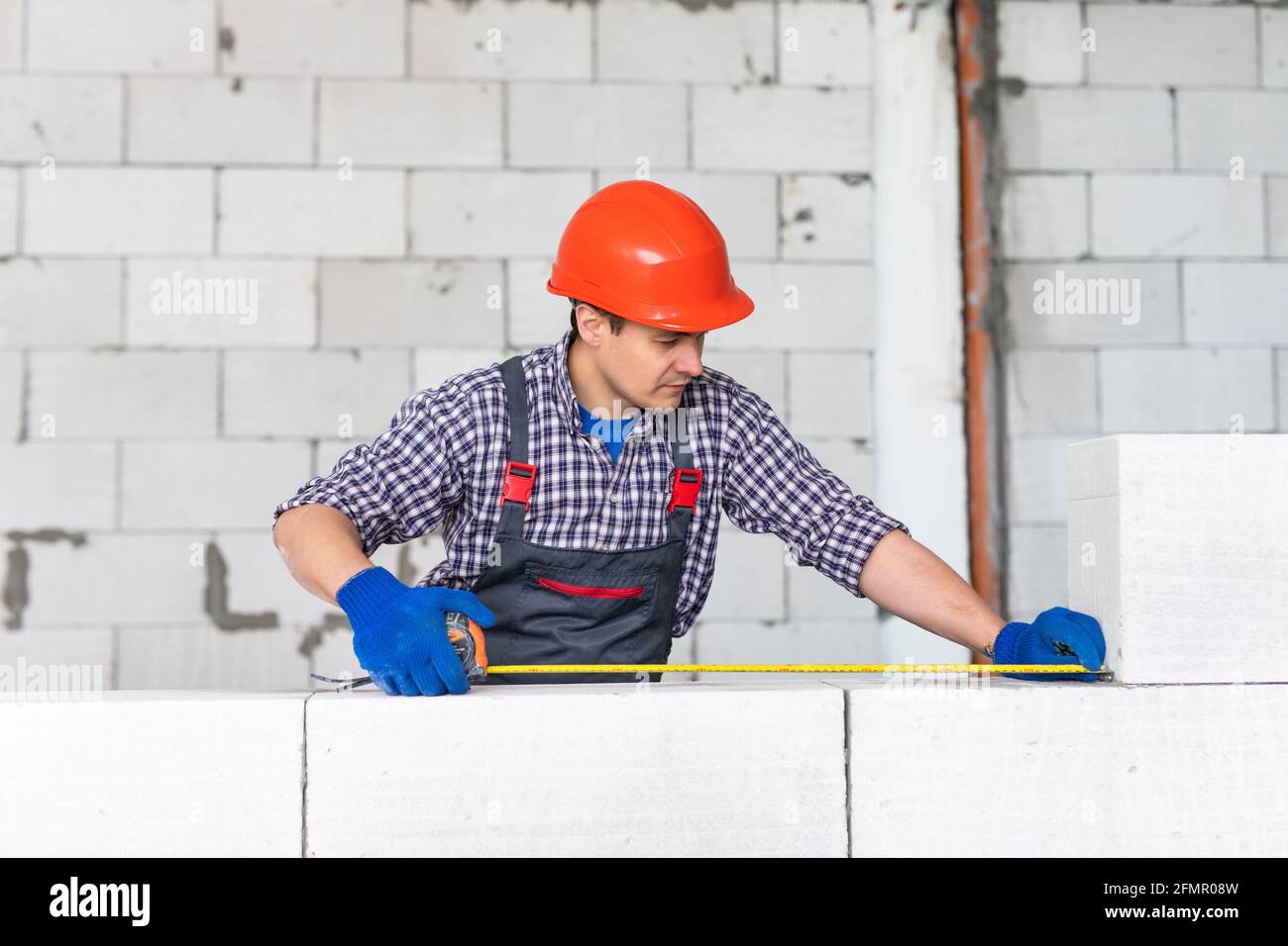 bricklayer man builder travaillant avec des blocs de béton cellulaire autoclavés. Mural Banque D'Images