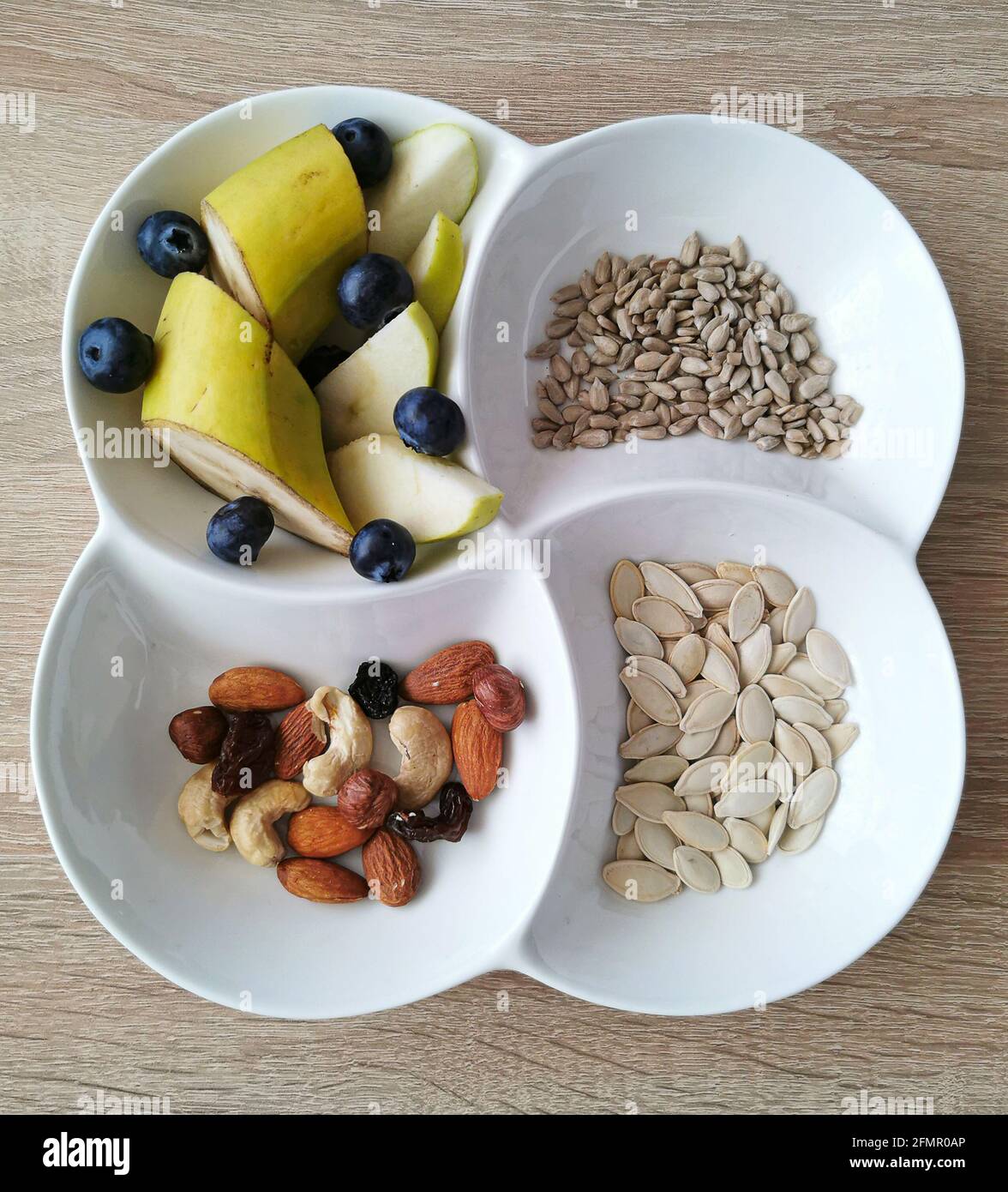 Une collation saine. Noix, graines de tournesol et de citrouille. Morceaux de banane, pommes et bleuets Banque D'Images