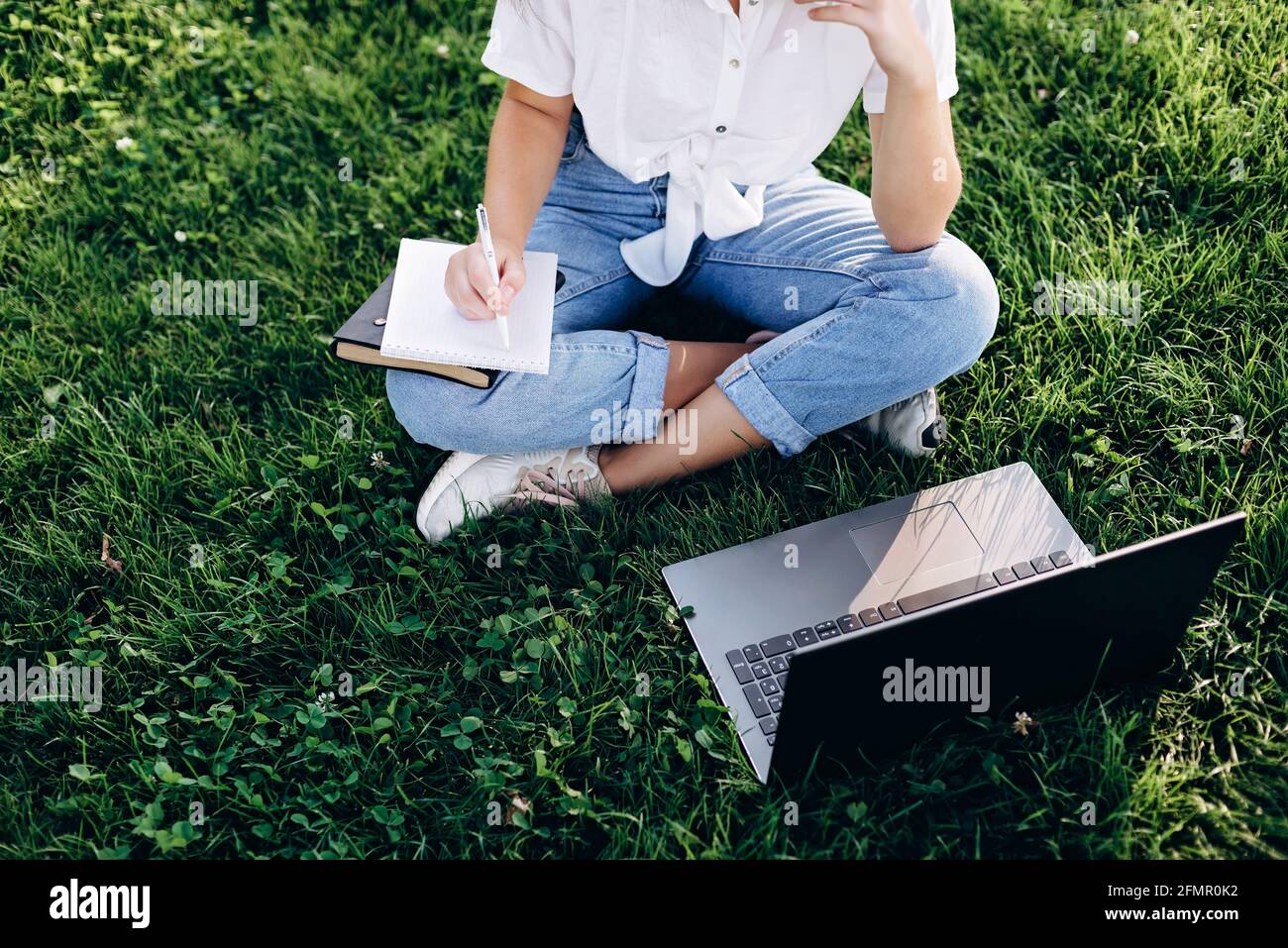 fille étudiante avec un ordinateur portable à l'extérieur assis sur l'herbe, surfer sur internet ou se préparer aux examens. Technologie, éducation et travail à distance. Donc Banque D'Images