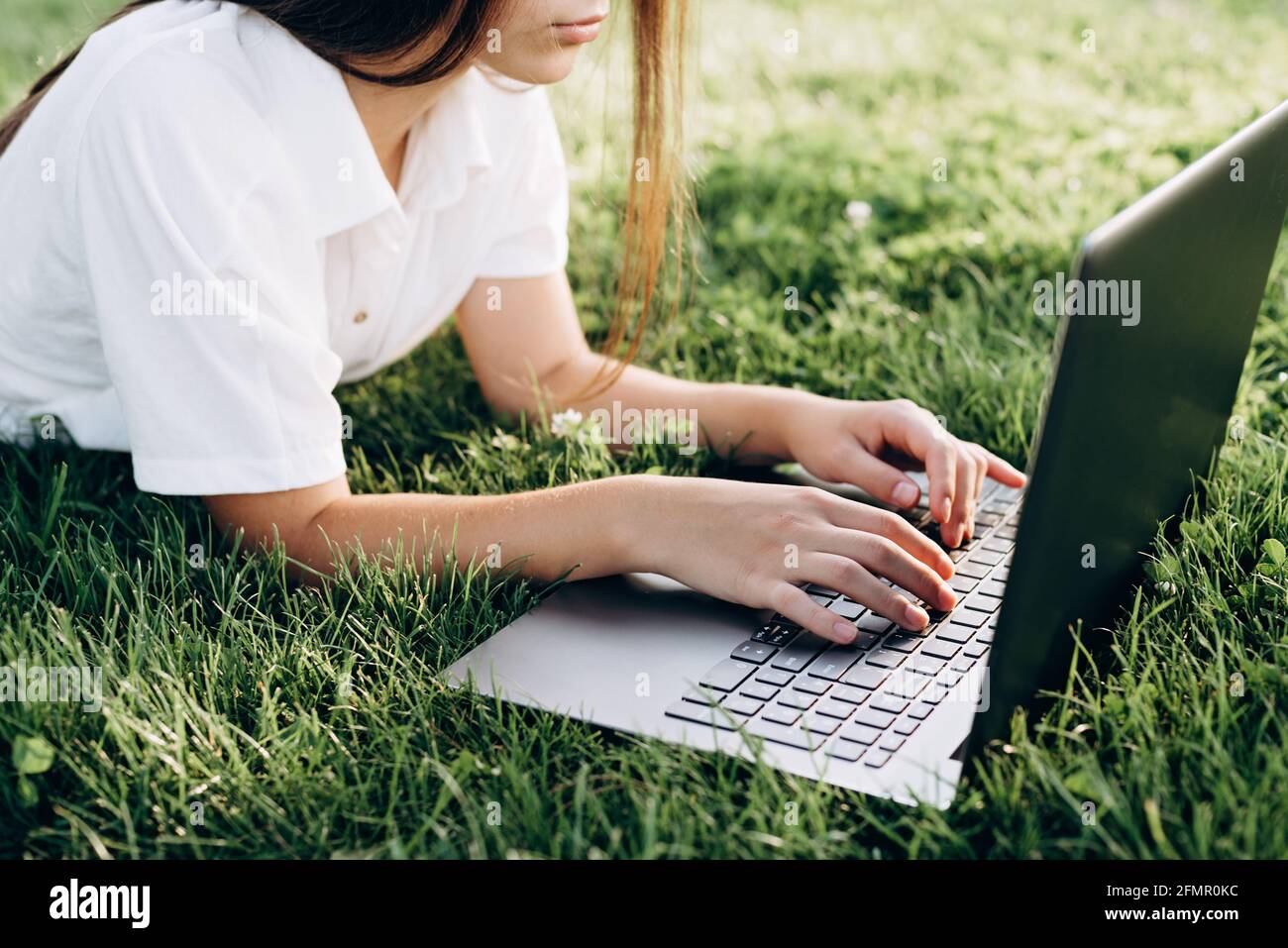 Fille étudiante avec ordinateur portable à l'extérieur. Femme couché sur l'herbe avec un ordinateur, surfer sur Internet ou se préparer aux examens. Technologie, éducation et re Banque D'Images