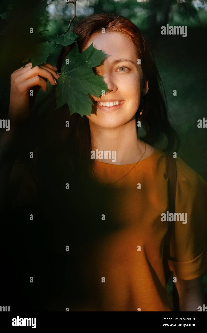 Portrait d'une jeune femme souriante avec des feuilles d'érable entre ses mains. Banque D'Images