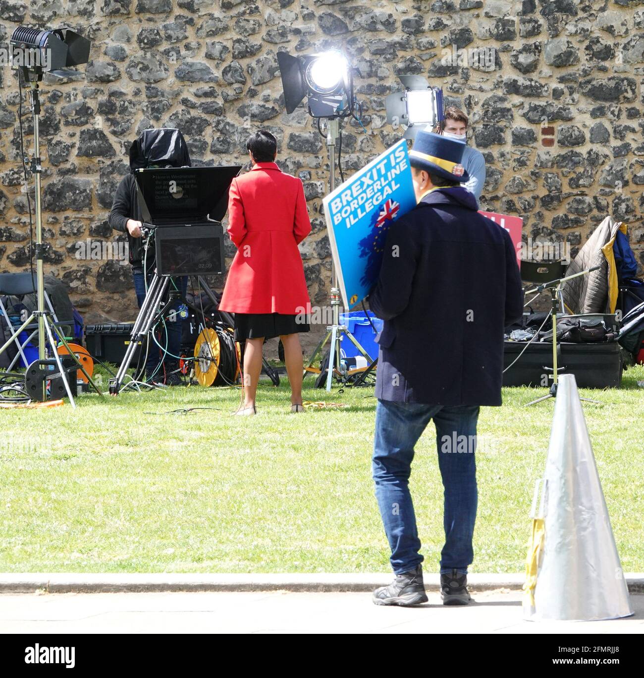 Westminster Londres, Royaume-Uni. 11th mai 2021. Reeta Chakrabarti de la BBC filmée sur le College Green face aux chambres du Parlement. Bien que la police ait réservé un accès aux médias au College Green, le célèbre manifestant anti-Brexit, Steve Bray, a été admis pour se tenir debout dans l'arrière-plan de la caméra, comme on l'a vu. Ouverture d'État du Parlement. À l'occasion d'une cérémonie à prix réduit, conforme à Covid, organisée par la Reine Elizabeth II, le Premier ministre Boris Johnson et d'autres intervenants, qui présente l'ordre du jour du gouvernement pour la prochaine session parlementaire. Credit: Andrew Stehrenberger / Alamy Live News Banque D'Images