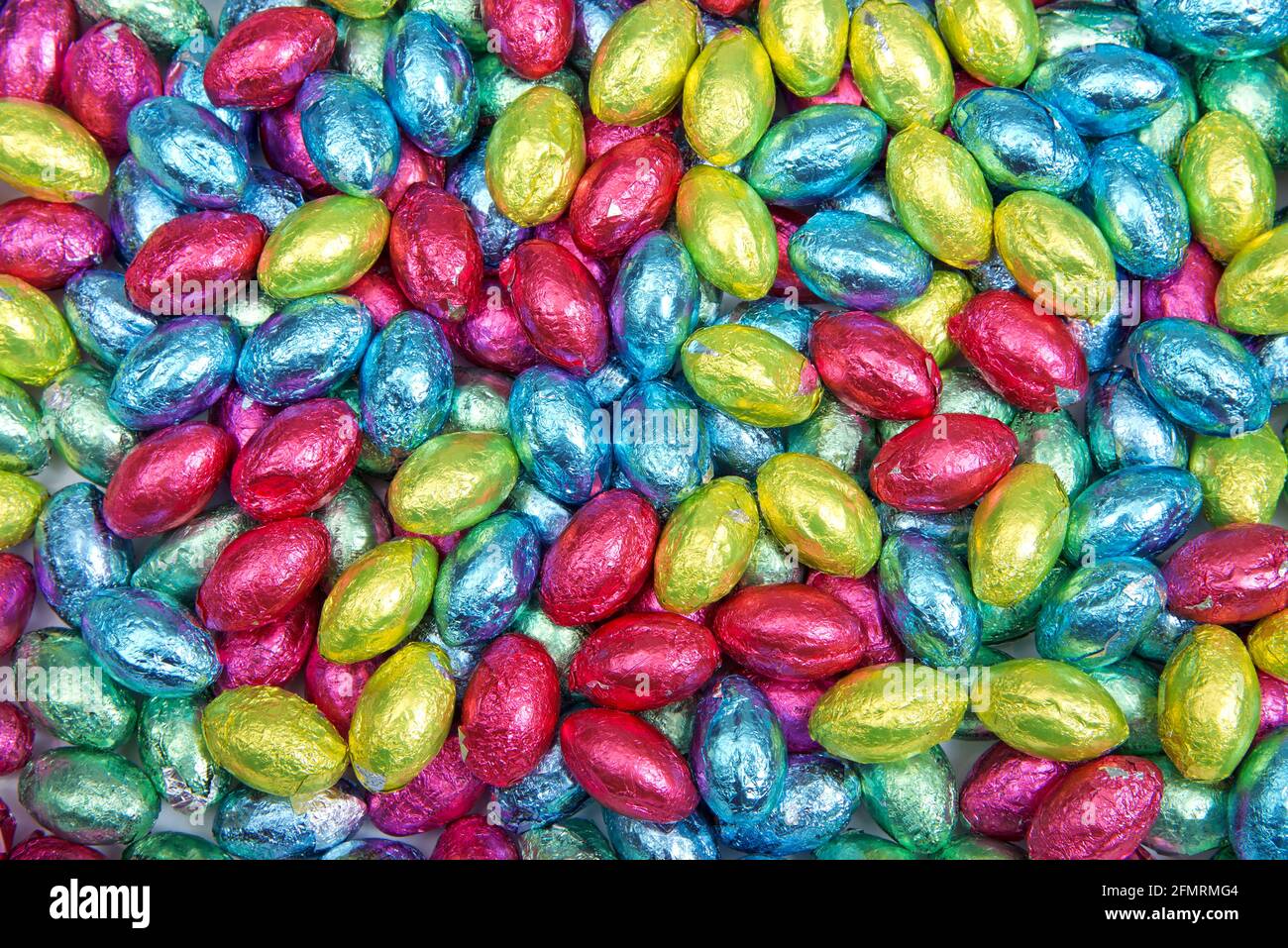 Gros plan sur les œufs de pâques au chocolat recouverts de couleurs vives enveloppeurs de feuilles de couleur Banque D'Images