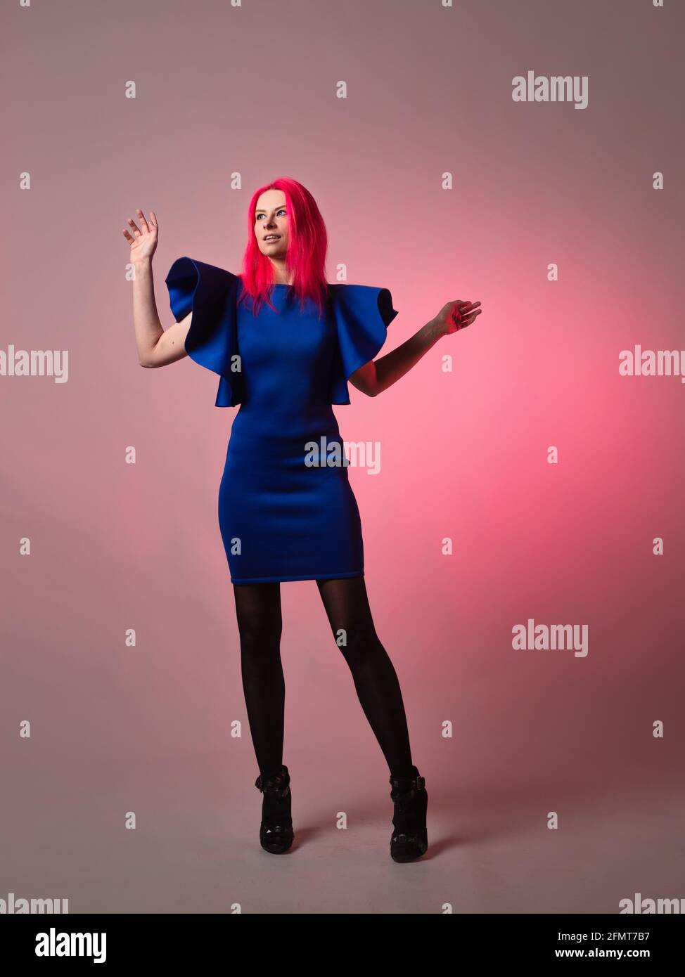 Belle et élégante tenue bleue sur une jeune femme attrayante avec des cheveux rose vif, mode moderne, portrait dans le studio sur un fond gris. Banque D'Images