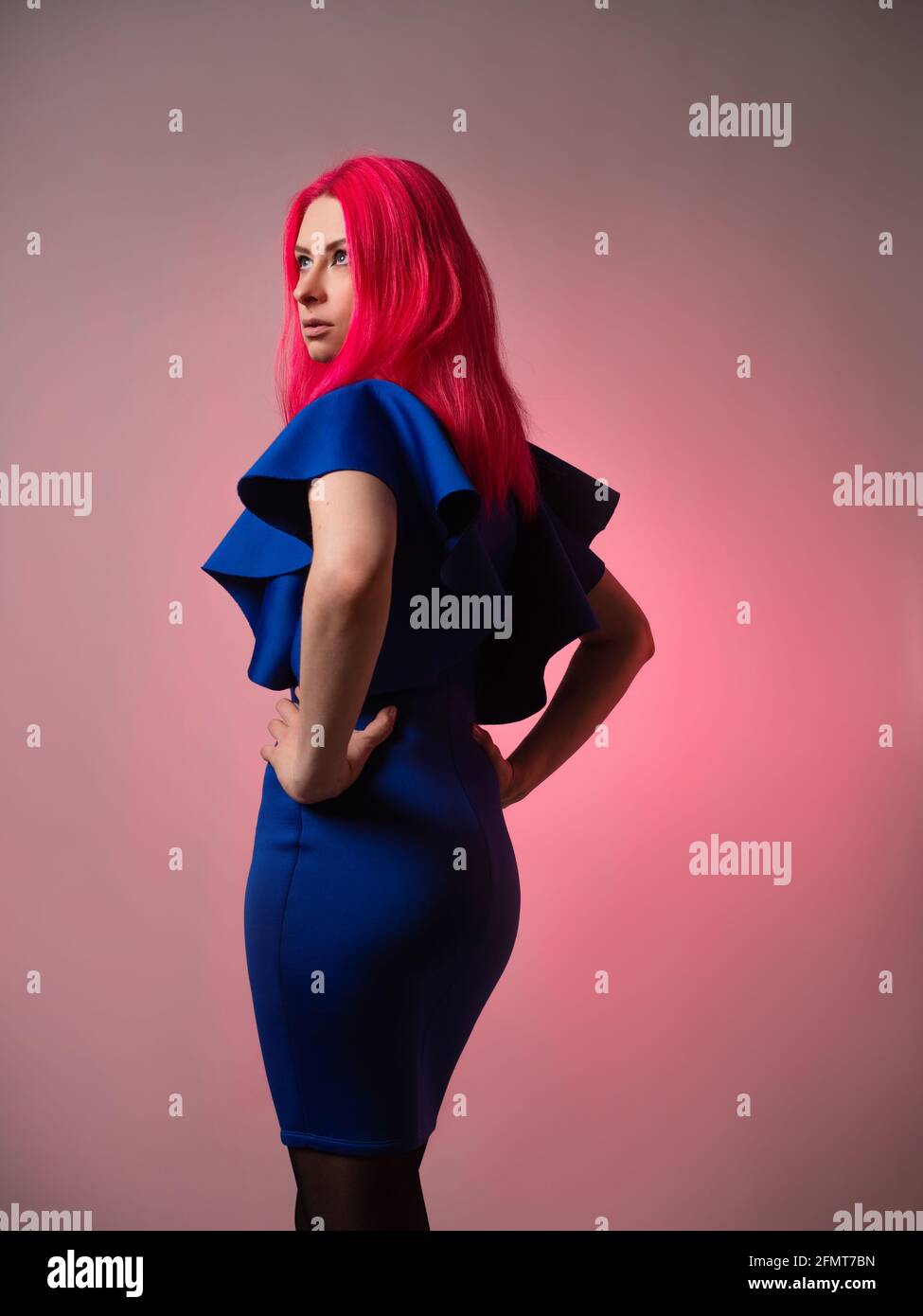 Belle et élégante tenue bleue sur une jeune femme attrayante avec des cheveux rose vif, mode moderne, portrait dans le studio sur un fond gris. Banque D'Images