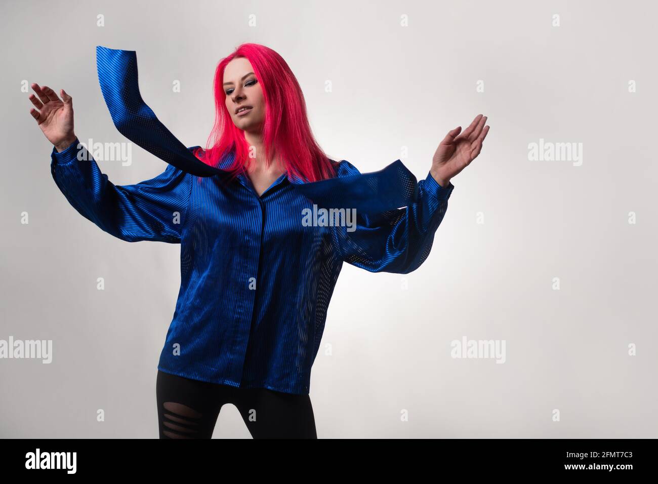 Belle et élégante tenue bleue sur une jeune femme attrayante avec des cheveux rose vif, mode moderne, portrait dans le studio sur un fond gris. Banque D'Images