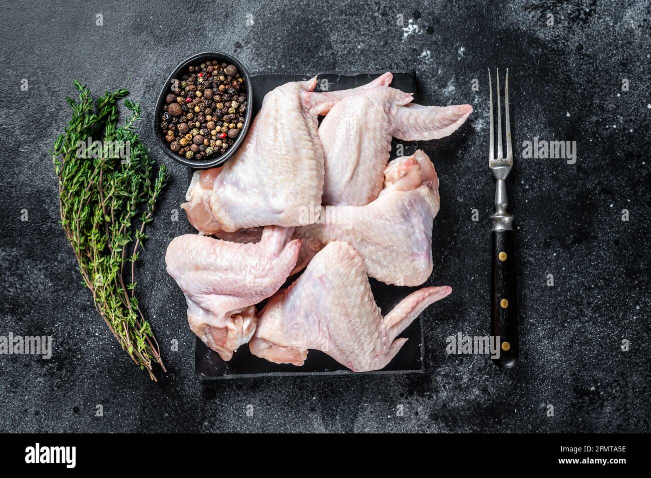 Ailes de poulet crues viande de volaille sur un plateau en marbre.  Arrière-plan noir. Vue de dessus Photo Stock - Alamy