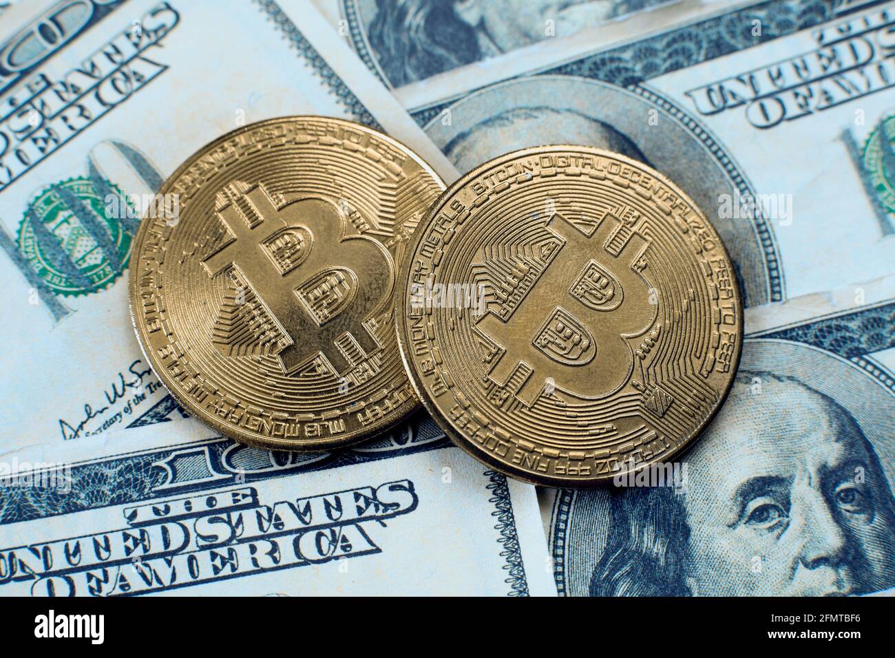 Deux pièces de crypto-monnaie bitcoin se trouvent sur cent dollars factures Banque D'Images