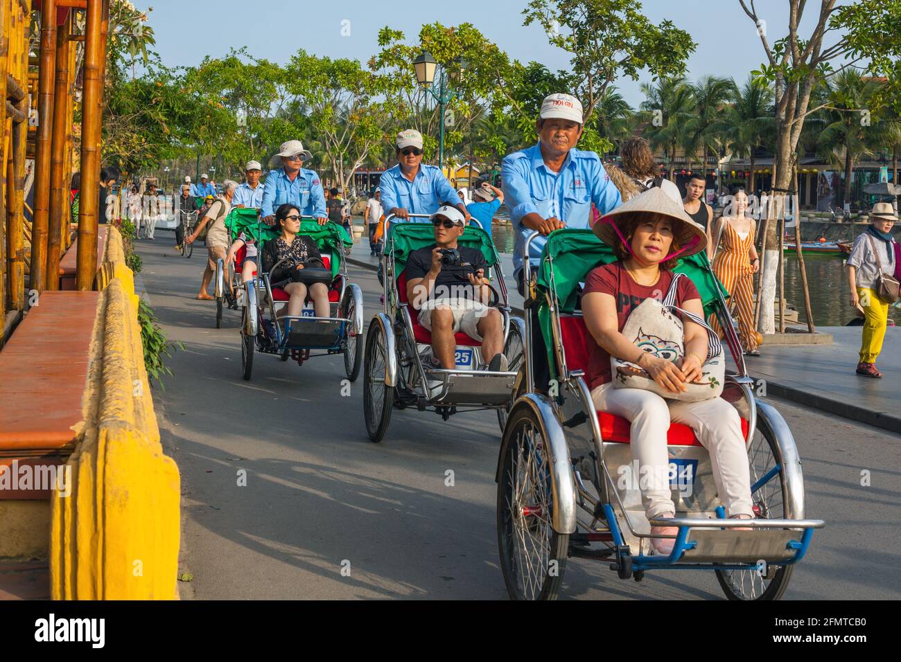 Les pilotes de cyclo chaffent les touristes le long du bord de la rivière dans la vieille ville, Hoi an, Vietnam Banque D'Images