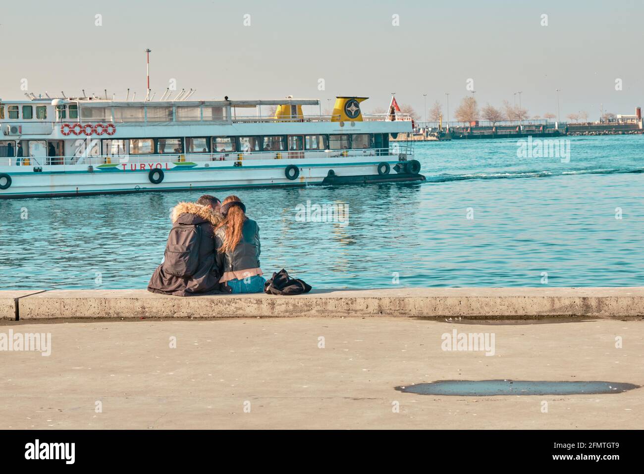 Deux jeunes couples et amoureux se embrassant et assis Aganst bosporus à Kadikoy istanbul pendant une journée ensoleillée avec passager ferry et turquoise Banque D'Images