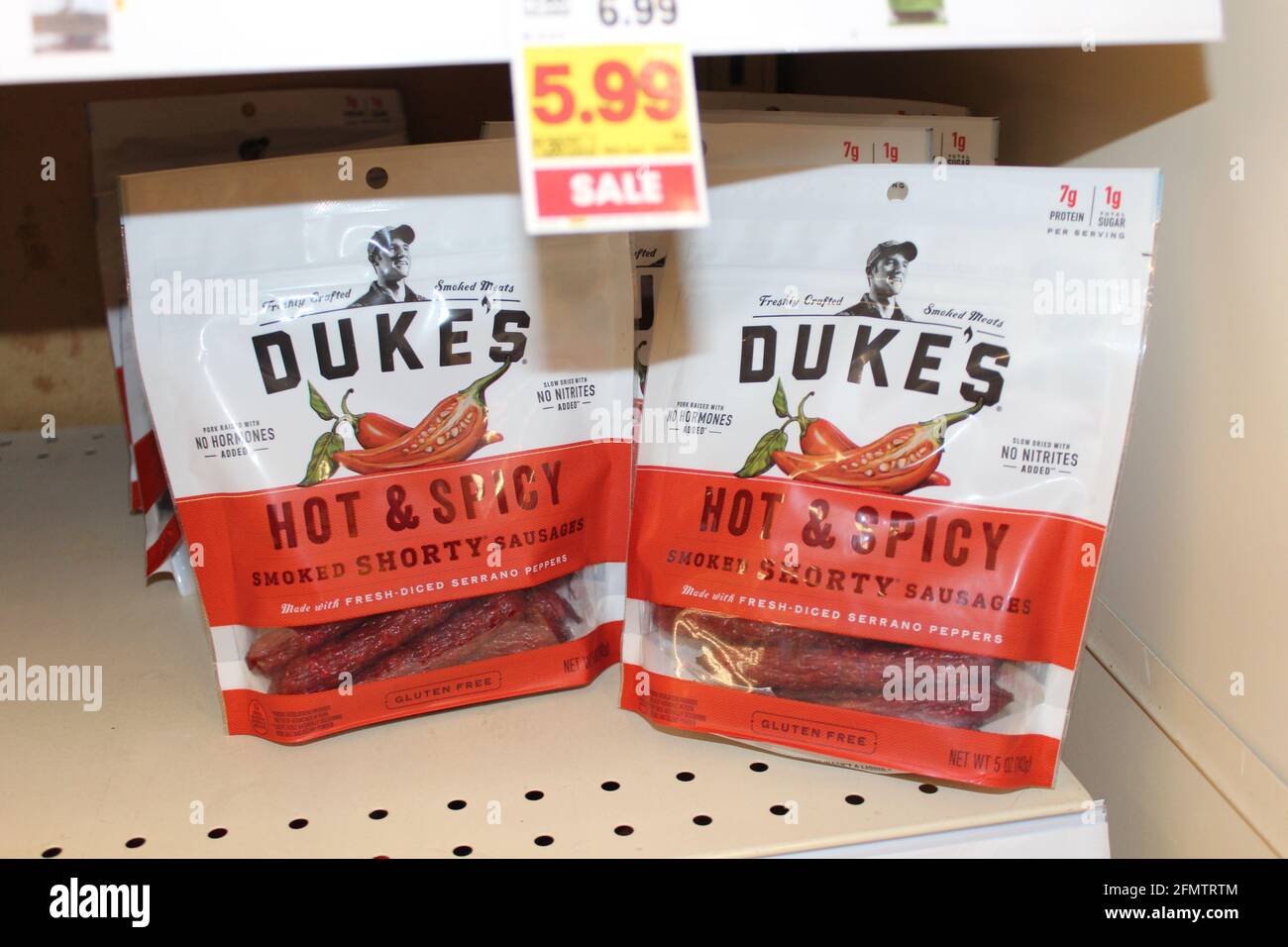 Les saucisses fumées Dukes Hot et Spicy qui sont dans des sacs en plastique sont lumineuses et colorées sur une étagère en métal dans une épicerie du Kansas qui est tourné de près. Banque D'Images