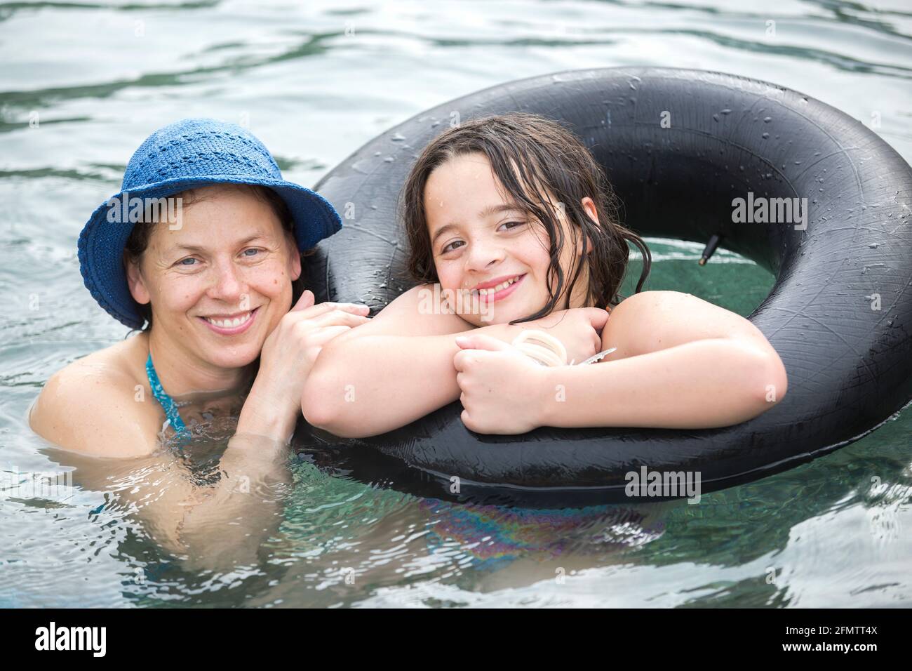 Portrait de la mère et de la fille de onze ans flottant dans la piscine Banque D'Images