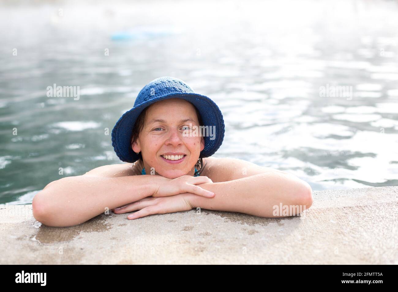 Portrait de la femme avec chapeau bleu reposant sur le bord de piscine de sources chaudes Banque D'Images