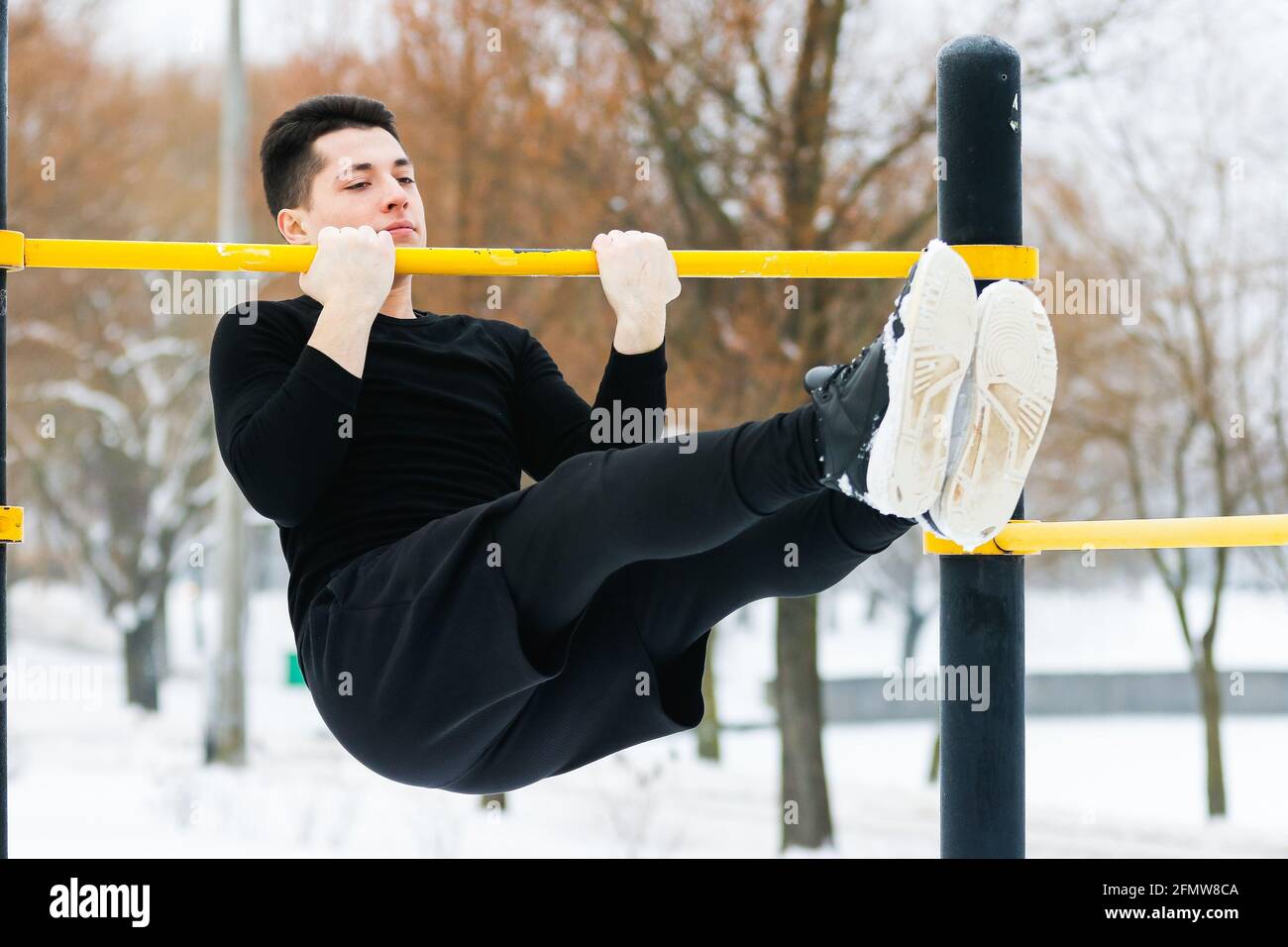 Un homme fait des pompes en hiver pendant les sports du matin avec l'aide de la machine d'exercice jaune. Banque D'Images