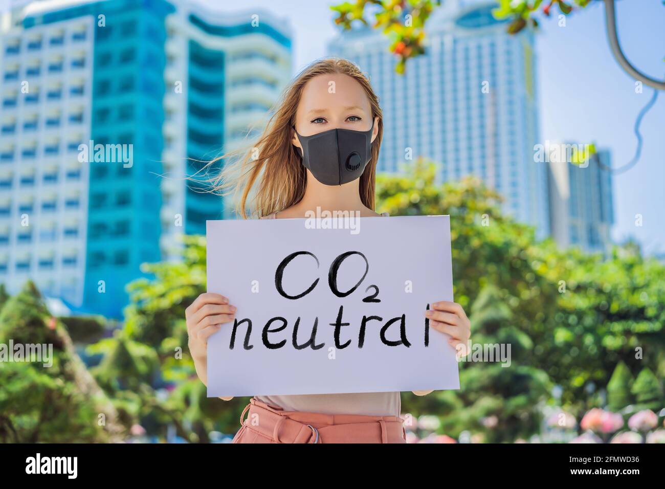 Femme dans le masque médical tient une affiche lettrage texte CO2 Neutre Banque D'Images